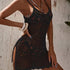 Woman wearing a black crochet dress against a textured wall.