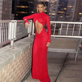 Woman in a red evening gown with cut-out design on a rooftop at night.